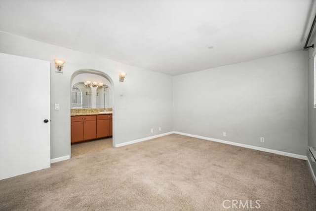 interior space featuring baseboards, light carpet, and arched walkways