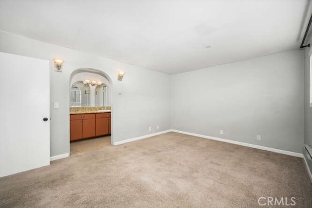 interior space with light colored carpet, arched walkways, and baseboards