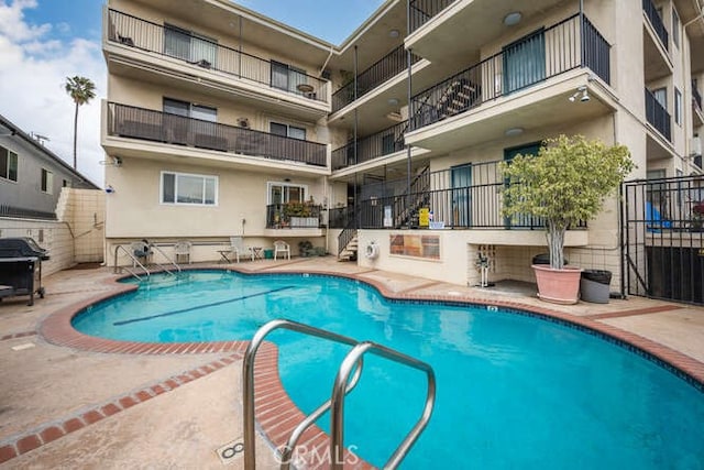 community pool with a patio area and grilling area