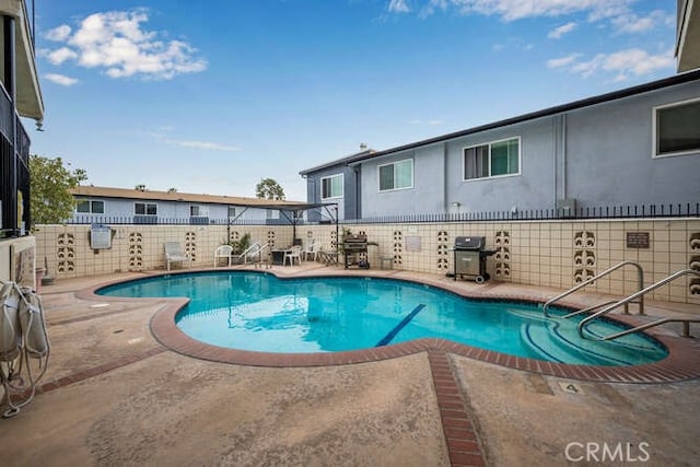 view of swimming pool with a patio, a fenced in pool, fence, and a grill