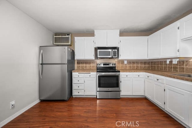 kitchen featuring an AC wall unit, white cabinetry, tile countertops, stainless steel appliances, and dark wood-style flooring