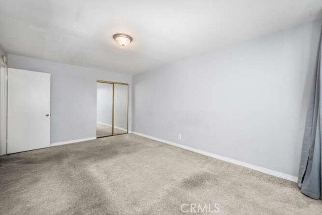 unfurnished bedroom featuring a closet, carpet flooring, and baseboards