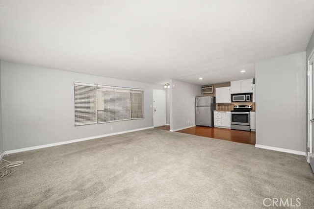 unfurnished living room with baseboards, recessed lighting, and carpet flooring