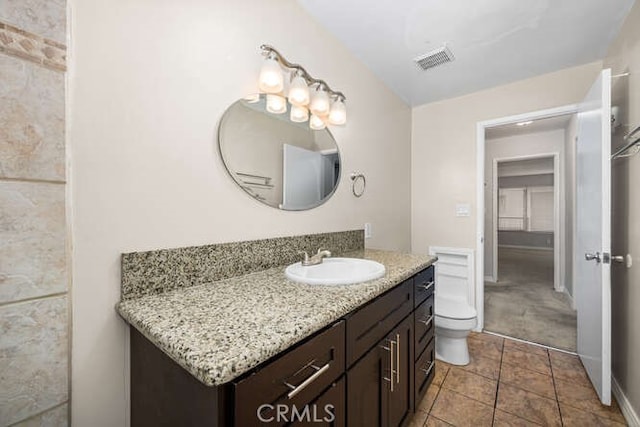 bathroom with vanity, baseboards, visible vents, tile patterned floors, and toilet