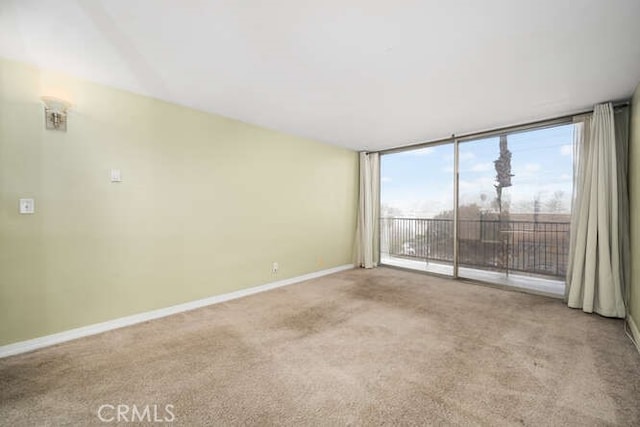 empty room featuring floor to ceiling windows, carpet flooring, and baseboards