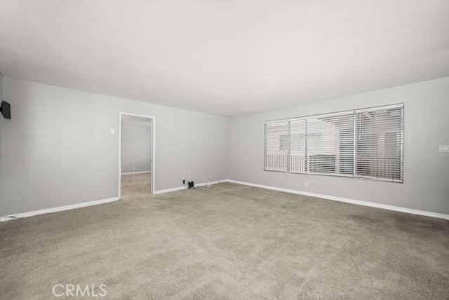 unfurnished room with carpet flooring and baseboards