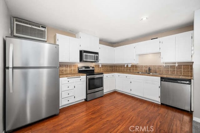 kitchen featuring tile countertops, white cabinets, a wall mounted AC, appliances with stainless steel finishes, and a sink