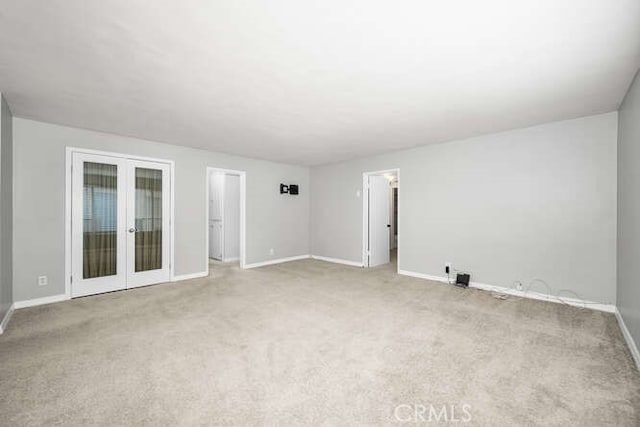 spare room with french doors, carpet floors, and baseboards