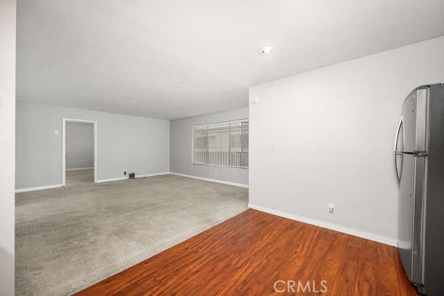 unfurnished living room with carpet flooring and baseboards