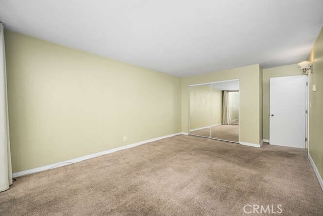 unfurnished bedroom with baseboards, carpet flooring, and a closet