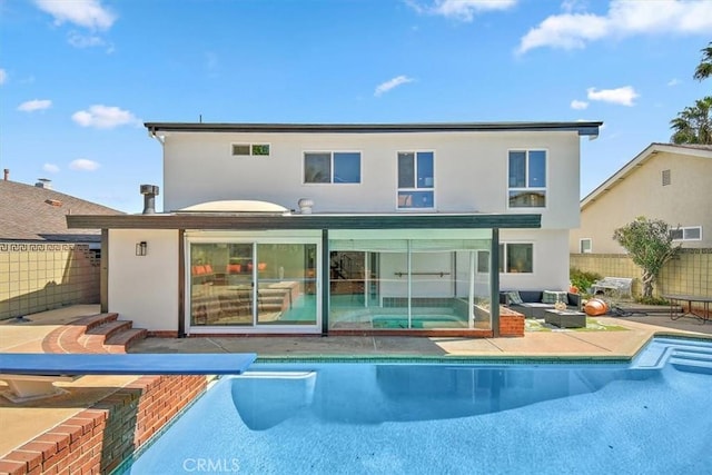 back of property with a patio, a fenced in pool, fence, and stucco siding