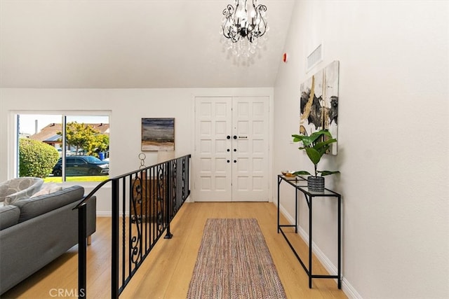 foyer entrance with visible vents, light wood-type flooring, a chandelier, and baseboards