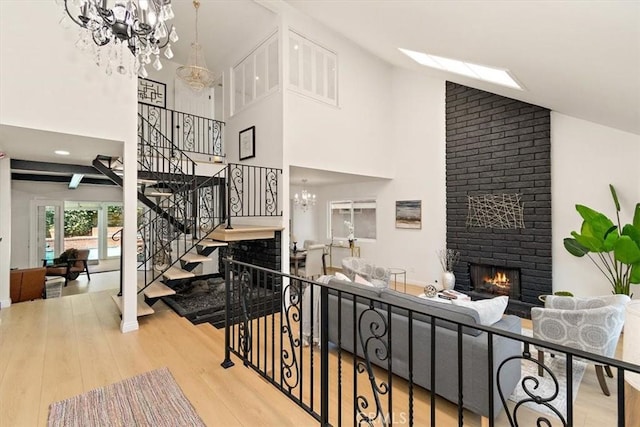 stairway with high vaulted ceiling, a notable chandelier, wood finished floors, and a fireplace