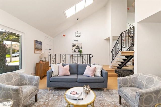 living room with high vaulted ceiling, wood finished floors, an inviting chandelier, a skylight, and stairs