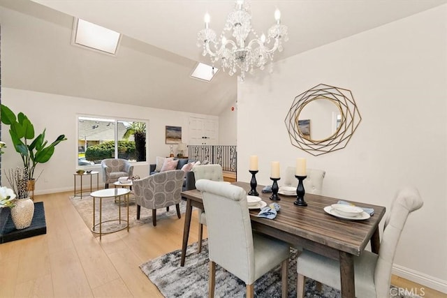 dining area with baseboards, lofted ceiling with skylight, an inviting chandelier, and light wood-style flooring