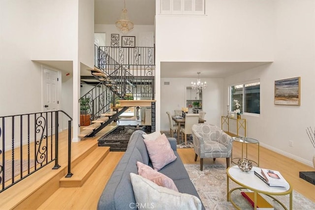 living room with wood finished floors, baseboards, stairs, a towering ceiling, and a notable chandelier