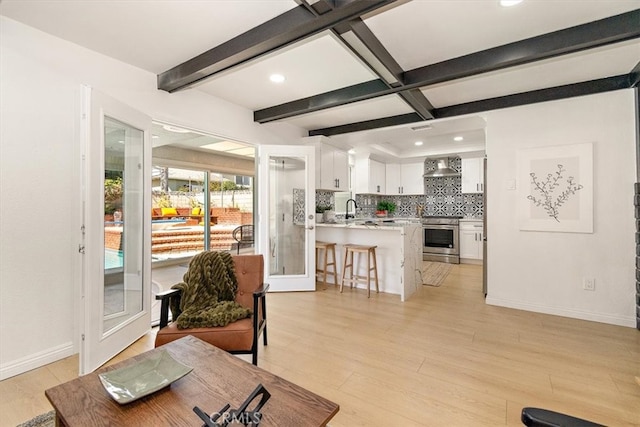 living area with beamed ceiling, recessed lighting, light wood-style flooring, and baseboards