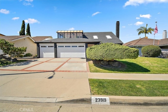 view of front of home featuring a front lawn, concrete driveway, and an attached garage