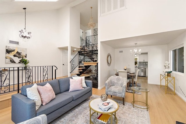 living area with an inviting chandelier, visible vents, and light wood-type flooring