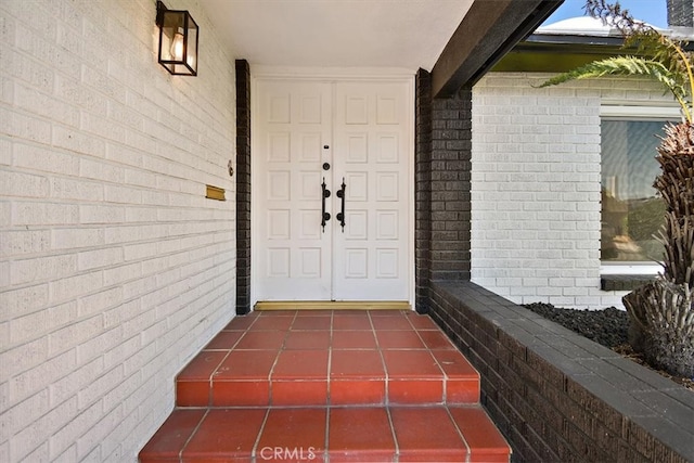 view of exterior entry with brick siding and a porch