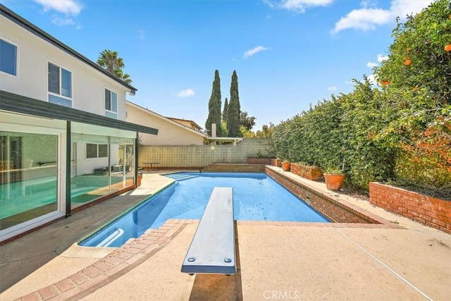 view of swimming pool featuring a patio area, a fenced in pool, a fenced backyard, and a diving board