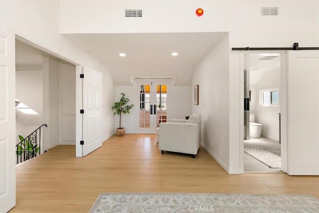 sitting room with french doors, visible vents, a wealth of natural light, and light wood-type flooring