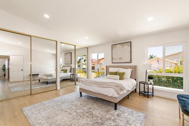 bedroom with multiple windows, two closets, and light wood-style floors