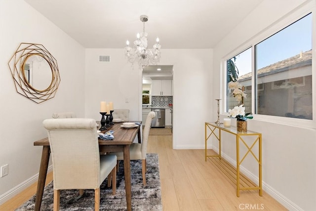 dining area with visible vents, plenty of natural light, light wood-type flooring, and an inviting chandelier