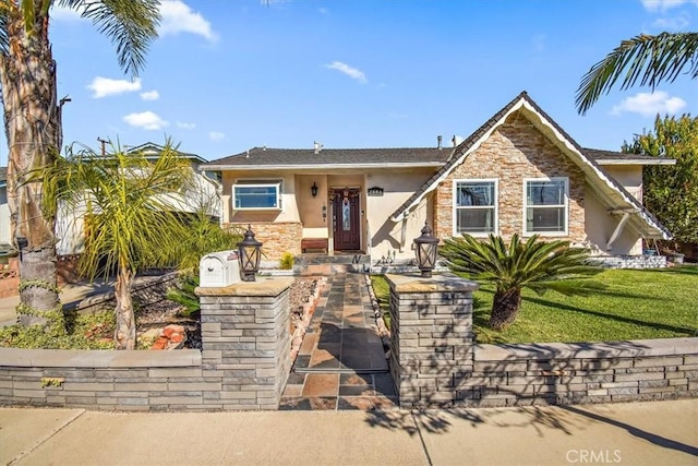 view of front of house with stucco siding, stone siding, and a front lawn