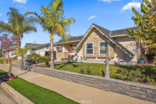 view of front of home with a front yard, stone siding, and stucco siding