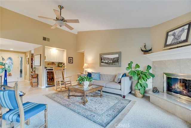 living room featuring visible vents, high vaulted ceiling, beverage cooler, a fireplace, and ceiling fan