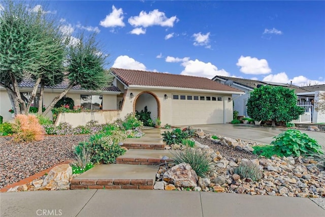 view of front facade with stucco siding, a tiled roof, concrete driveway, and a garage