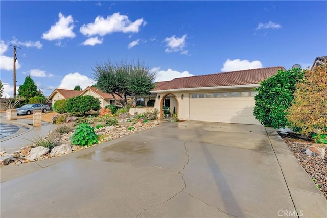 single story home with concrete driveway, an attached garage, a tile roof, and stucco siding