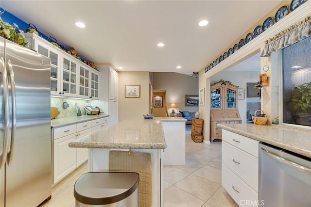 kitchen with recessed lighting, stainless steel appliances, glass insert cabinets, and a kitchen island