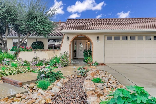 view of front of home featuring stucco siding, driveway, a tile roof, and an attached garage