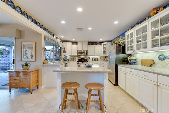 kitchen featuring stainless steel appliances, tasteful backsplash, light tile patterned flooring, and a center island