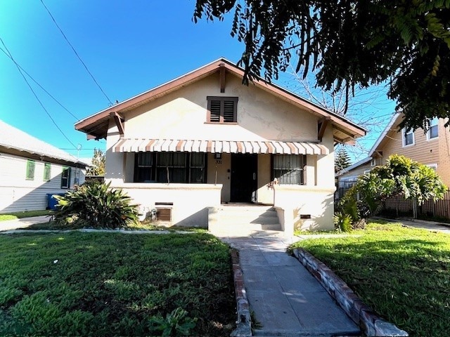 bungalow-style home with stucco siding, a porch, and a front yard