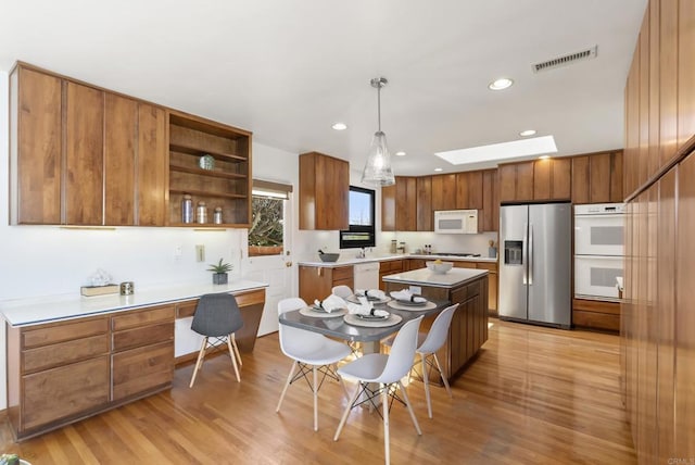 kitchen featuring visible vents, a skylight, light wood-style floors, white appliances, and open shelves