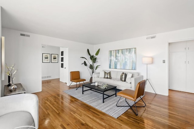 living area with visible vents and wood finished floors