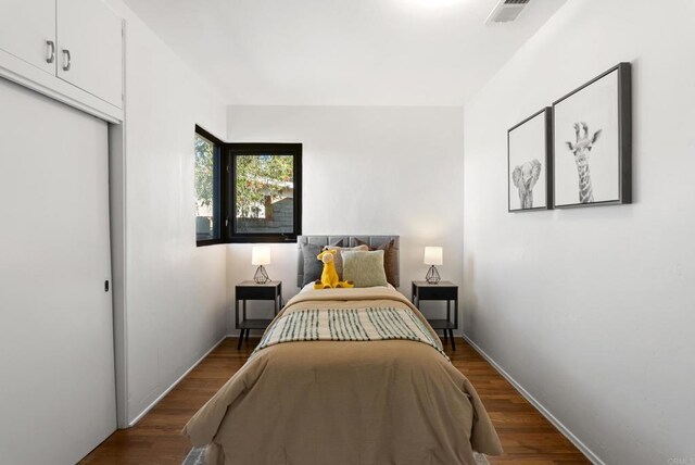 bedroom featuring dark wood finished floors, visible vents, and a closet