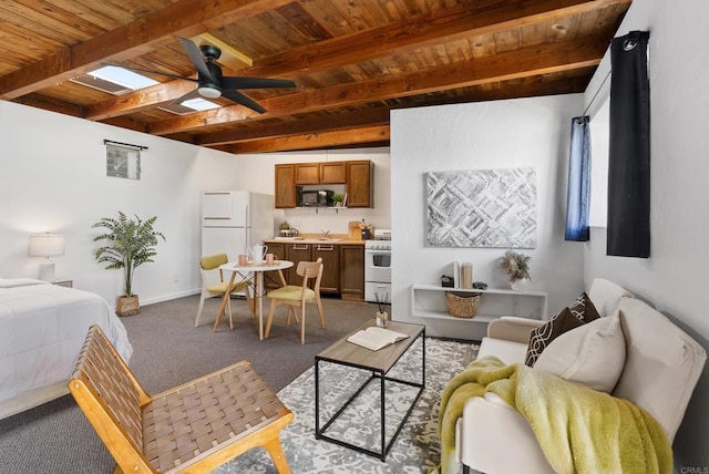 interior space featuring baseboards, freestanding refrigerator, a sink, wooden ceiling, and beamed ceiling