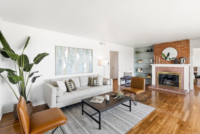 living room featuring visible vents, wood finished floors, and a fireplace