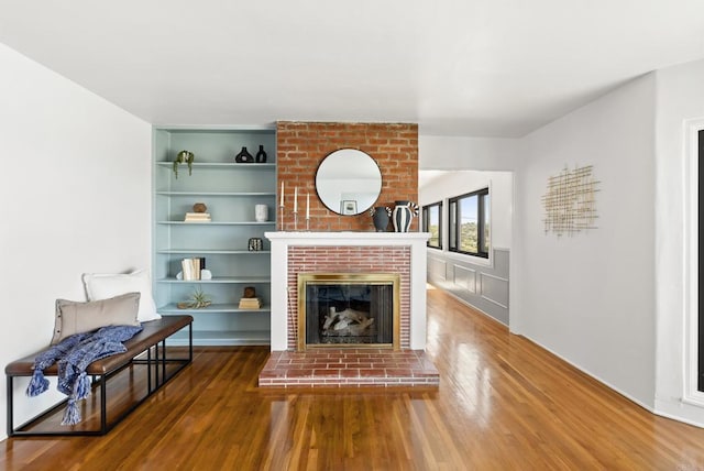 living room featuring wood-type flooring, built in shelves, and a fireplace