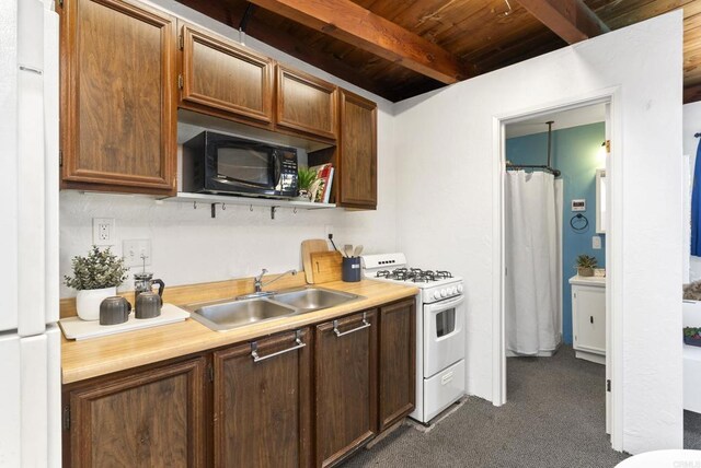 kitchen with white appliances, beam ceiling, a sink, light countertops, and dark colored carpet