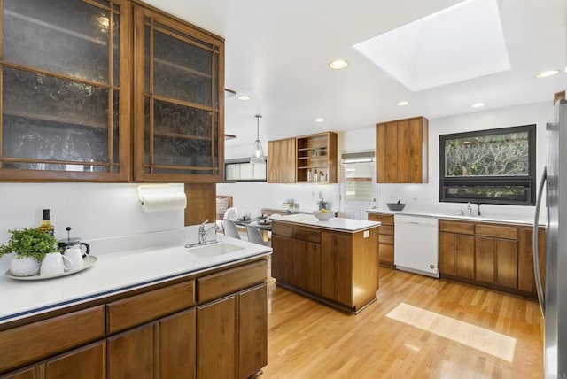 kitchen featuring a sink, freestanding refrigerator, light wood-style floors, white dishwasher, and light countertops