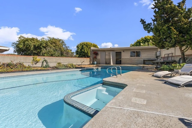 view of swimming pool with a patio, fence, and a pool with connected hot tub