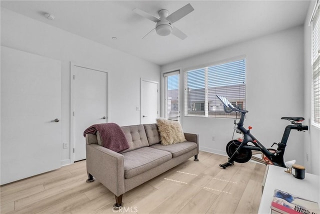 exercise room featuring light wood-style flooring, baseboards, and ceiling fan