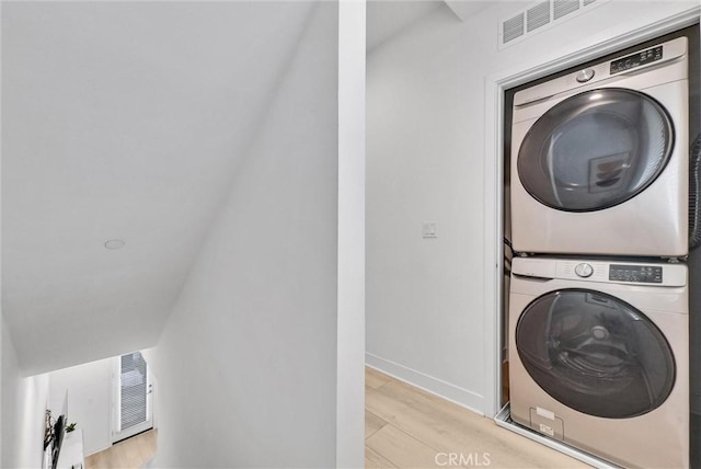 washroom featuring laundry area, stacked washer / dryer, visible vents, and light wood finished floors