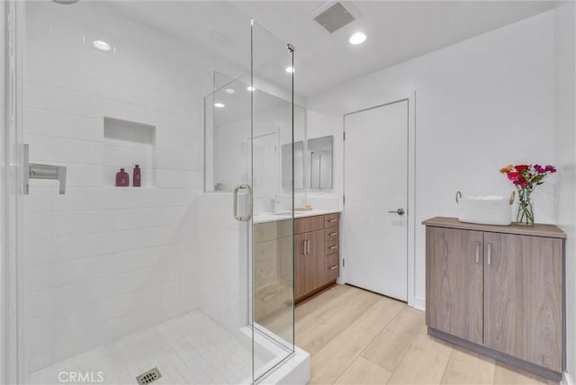 full bathroom featuring visible vents, a shower stall, wood finished floors, and vanity