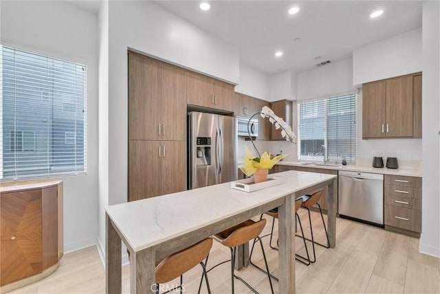 kitchen featuring light wood-type flooring, stainless steel appliances, recessed lighting, and a sink